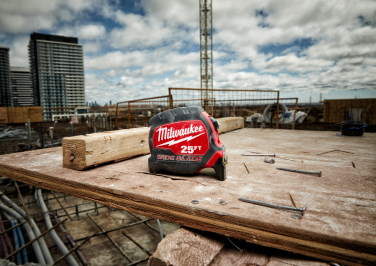 A Milwaukee tape measure sits on a makeshift work bench on a construction site in the city