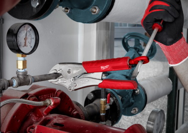 Gloved hand uses a Milwaukee Screwdriver as leverage to turn a pair of Milwaukee pliers on a valve