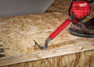 A hand in a Milwaukee work glove uses a Milwaukee pry bar to pry a nail from a plywood step