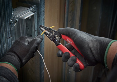 Gloved electrician's hands use a Milwaukee wire-stripper tool to repair an electrical outlet.