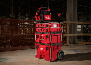 A series of Milwaukee PACKOUT toolboxes sit stacked on a PACKOUT cart at a construction site