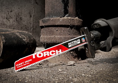 A Milwaukee TORCH Sawzall blade rests against a cast iron pipe on a jobsite.